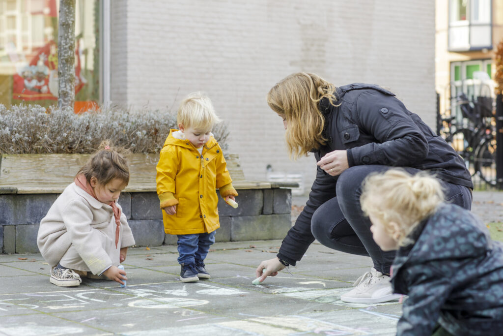 Pedagogisch medewerker speelt buiten met peuters bij Altijd Lente